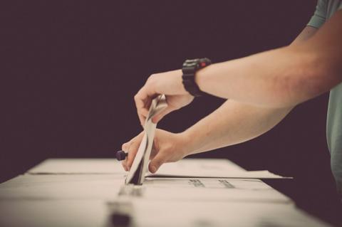 Un hombre está colocando una boleta en una urna de votación.