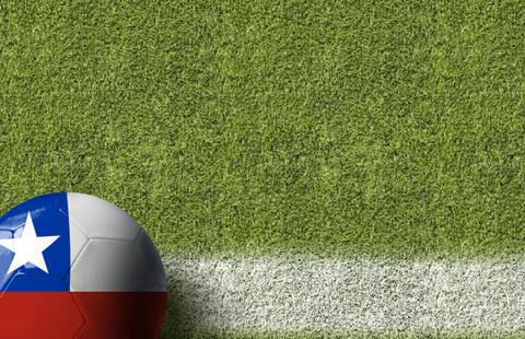 Una pelota de fútbol con los colores de la bandera de Chile sobre un campo de césped.
