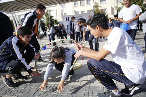 Un grupo de jóvenes participa en actividades al aire libre, utilizando aros mientras se divierten en un evento escolar.