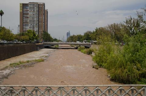 Un río de aguas turbias rodeado de edificios y vegetación en una ciudad.