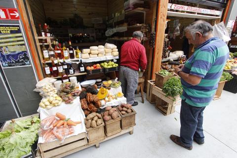 Una escena de un mercado donde hay una variedad de frutas y verduras frescas en cajas de madera.