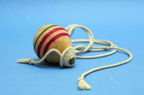 Un trompo de madera con colores vibrantes y una cuerda enrollada a su alrededor.