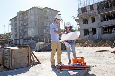 Dos profesionales discuten sobre planos de construcción en un sitio de obra.
