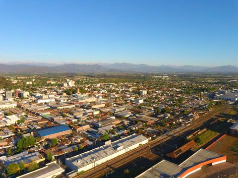 Vista aérea de una ciudad con montañas al fondo y una variedad de edificios y calles.