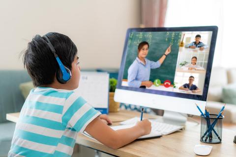 Un niño está aprendiendo en línea mientras utiliza una computadora con un docente y compañeros en videollamada.