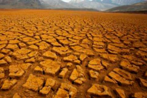 La imagen muestra un terreno árido y agrietado, representando la sequía y la falta de agua.