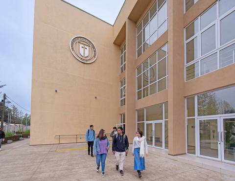 Un grupo de estudiantes caminando frente a un edificio moderno de la universidad.