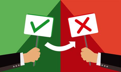 Dos manos sostienen carteles que representan aprobación y desaprobación.