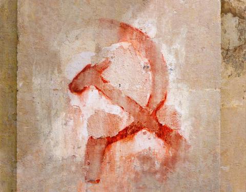 Una pintura desgastada de un símbolo comunista en una pared.