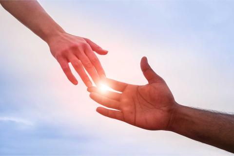 Dos manos se extienden hacia adelante, conectando con un brillo de luz entre ellas.