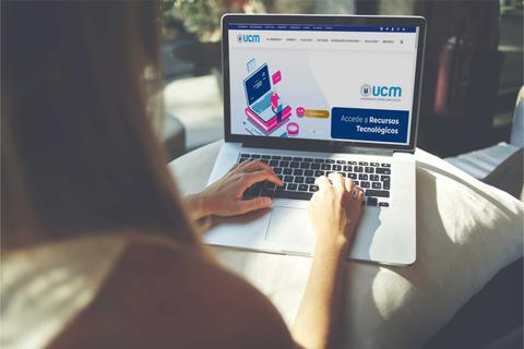 Una persona está usando un ordenador portátil con una página web abierta que parece pertenecer a la UCM.