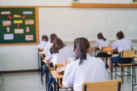 Un grupo de estudiantes sentados en pupitres realizando un examen en un salón de clases.