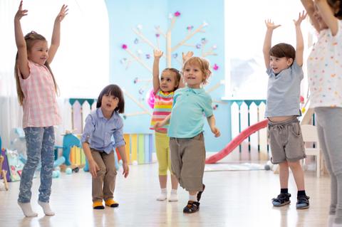 Un grupo de niños están disfrutando y bailando en una sala luminosa.