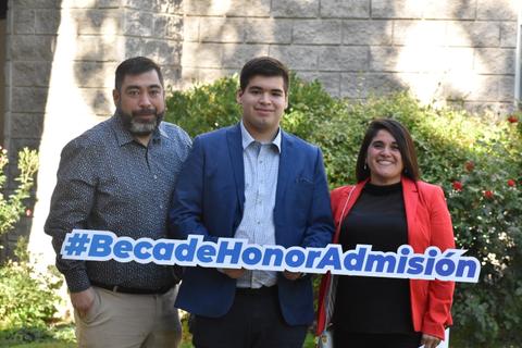 Tres personas sosteniendo un cartel que dice '#BecadeHonorAdmisión' en un entorno al aire libre.