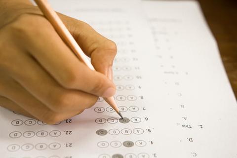 Una mano marcando respuestas en un examen de opción múltiple.