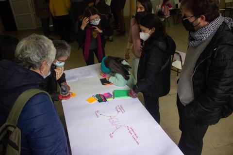 Grupo de personas colaborando en un proyecto sobre el agua en una reunión comunitaria.