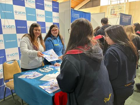 Una feria educativa donde se están entregando folletos a estudiantes interesados.