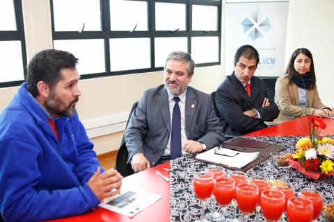 Una reunión en una sala con cuatro personas sentadas alrededor de una mesa roja con bebidas sobre ella.