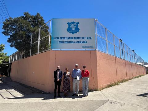 Cuatro personas posan frente al Liceo Bicentenario Oriente de Talca en un día soleado.
