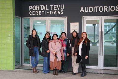 Un grupo de seis mujeres posando frente a un edificio que lleva el nombre 'Portal Tevu Cereti-Daas'.