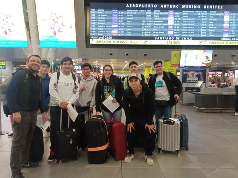 Un grupo de personas posando en un aeropuerto con maletas.