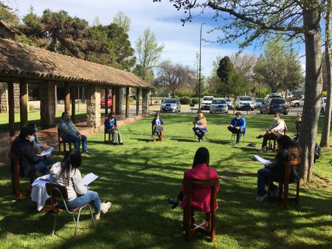Un grupo de personas se reúne en un espacio al aire libre para discutir o trabajar en un proyecto.
