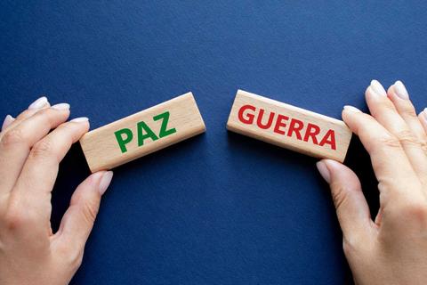 Las manos sostienen bloques de madera con las palabras 'Paz' y 'Guerra'.