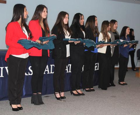 Un grupo de mujeres de pie sostiene mantas en un evento formal.