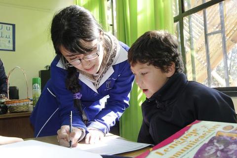 Una maestra está ayudando a un niño a hacer una tarea en un aula.