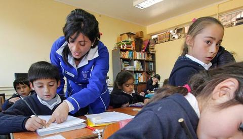 Una maestra enseña a sus alumnos en un aula escolar.
