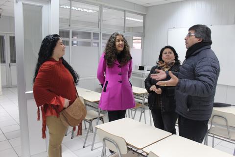 Un grupo de cuatro personas conversando en un aula.