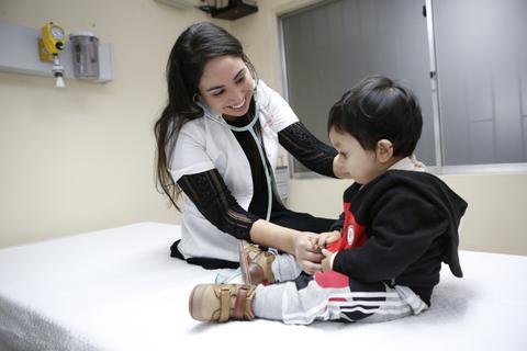 Una doctora revisa a un niño pequeño en un consultorio médico.