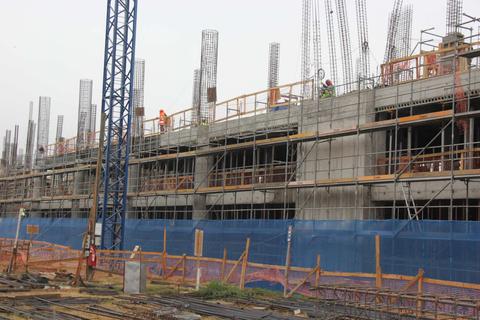 Un sitio de construcción con estructuras de hormigón y trabajadores en las grúas.