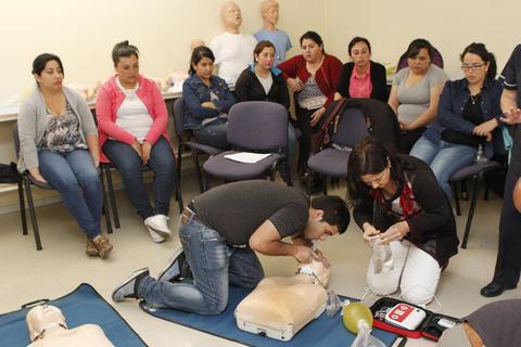 Un grupo de personas observa una demostración de reanimación cardiopulmonar sobre un maniquí.