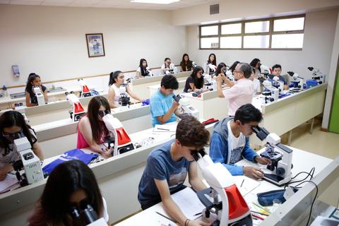 Un grupo de estudiantes trabaja en un aula utilizando microscopios.