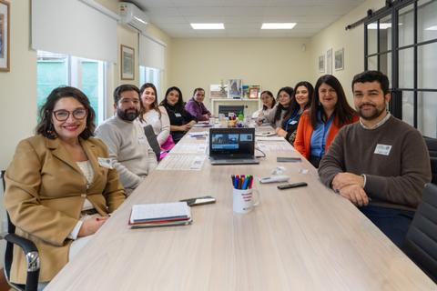 Un grupo de profesionales reunidos en una mesa grande, conversando y compartiendo ideas.
