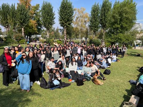 Un grupo grande de personas posando juntas en un parque en un día soleado.