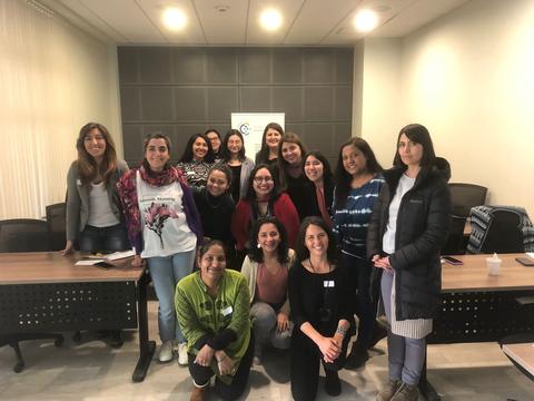 Un grupo de mujeres sonrientes posando en una sala de reuniones.