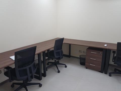 Una oficina con escritorios de madera y sillas ergonómicas.