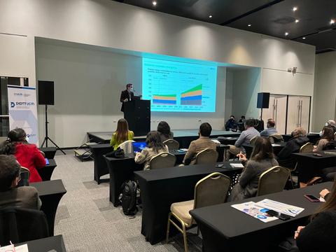 Una presentación en una conferencia con un ponente frente a una audiencia de profesionales.