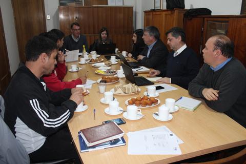 Una reunión de trabajo en una mesa con varias personas discutiendo y comiendo.