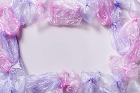 Una colección de bolsas de plástico en tonos morados y rosas dispuestas en un marco alrededor de un fondo claro.