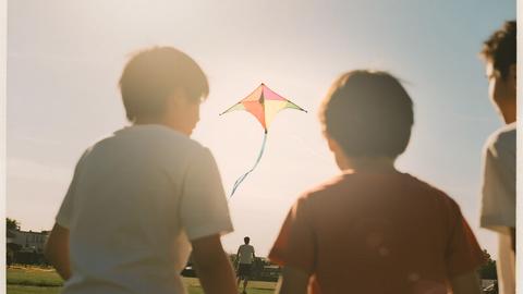 Un grupo de niños disfruta de un día soleado volando un papalote en el parque.