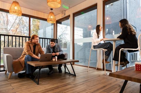 Grupo de amigos conversando y trabajando en un café acogedor.