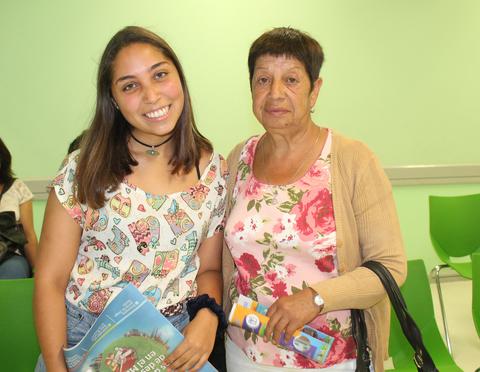 Una joven sonriente está junto a una mujer mayor en un ambiente familiar y acogedor.