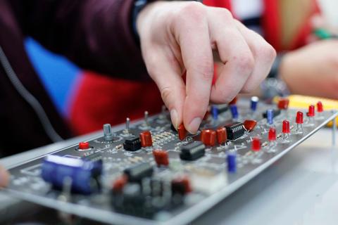 Una mano ajusta componentes en una placa de circuito.