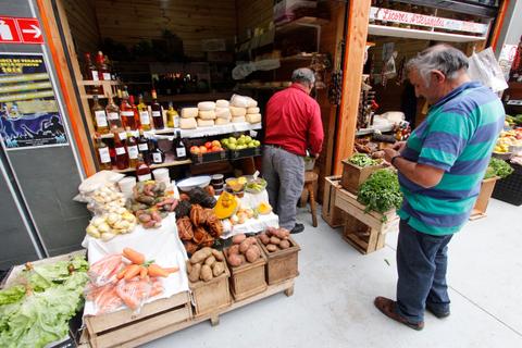Dos hombres comprando en un mercado de frutas y verduras.