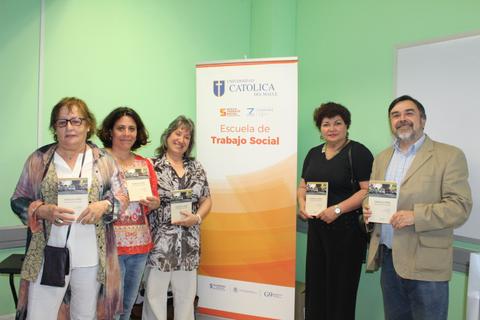 Un grupo de cinco personas sostiene diplomas frente a un banner de la Escuela de Trabajo Social.