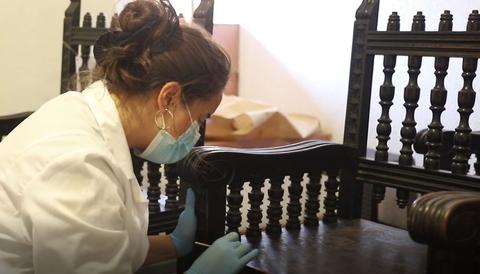 Una persona está restaurando una silla antigua en un taller.