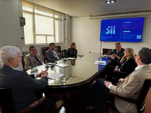Un grupo de personas se encuentra en una reunión alrededor de una mesa en una sala de conferencias.